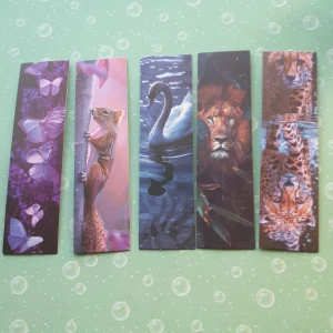 Bokmärken med djurmotiv - Säljer ett set med fem bokmärken med olika djurmotiv. Motiven inkluderar fjärilar, ekorre, svan, lejon och gepard. Perfekt för djurälskare och bokentusiaster. Bokmärkena är ca 15 cm långa och 4 cm breda.