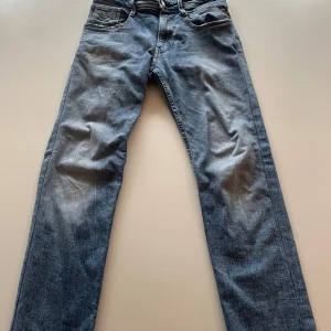 Blåa jeans från Replay - Snygga blåa jeans från Replay (anbass)med klassisk femficksdesign och broderad detalj på bakfickan. Jeansen har en slimfit passform och är tillverkade i slitstarkt denim. Perfekta för en avslappnad/grisch stil. Passar dig runt 160-170