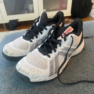 Vita träningsskor från wilson - Säljer ett par vita träningsskor från wilson med svarta detaljer och snörning. Skorna har en luftig mesh-design och en stabil sula, perfekt för inomhusträning. Märket syns tydligt på plösen. De är nötta på tån på utsidan.  Nypris ca 700kr säljer för 230kr. Priset går att diskutera 