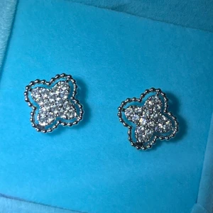 Äkta Silverfärgade örhängen med glittriga detaljer - Snygga silverfärgade örhängen i form av blommor med glittriga stenar. Perfekta för att ge en touch av elegans till din outfit. Kommer i en fin blå ask. Äkta silver 925