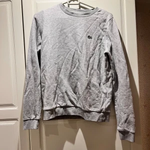 Lacost tröja - Säljer min Lacost tröja nu bör den är för liten Har små refelx likande detaljer på ena ärmen  Jättefint skick knappt använd  Storlek 34-36/s-xs