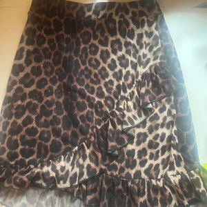 Leopardmönstrad kjol med volang - Säljer en supercool leopardmönstrad kjol med volangdetaljer. Kjolen har en omlottstil som ger en snygg och trendig look. Perfekt för en utekväll eller fest! 🐆✨