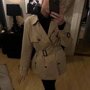 Beige trenchcoat - Säljer en snygg beige trenchcoat med klassiska detaljer som knappar och bälte i midjan. Jackan har långa ärmar och en stilren design som passar perfekt för både vår och höst. Perfekt för att ge en chic touch till din outfit! 🫶🍁❤️