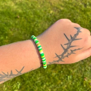 Grönt och vitt pärlarmband - Säljer ett superfint armband med gröna och guldiga pärlor. Perfekt för att ge lite färg till din outfit! Armbandet är elastiskt och passar de flesta handleder. Perfekt accessoar för sommaren! 🌿