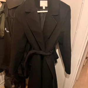 Svart fodrad kappa  - Säljer denna höst/ vinterkappa från hm  Inköpt förra vintern för 600kr från HM Säljer nu för 300! Använd väldigt fåtal gånger och normal i storlek.  Lång på mig som är 175, så perfekt till en mysig vinter outfit. Skriv för mer frågor