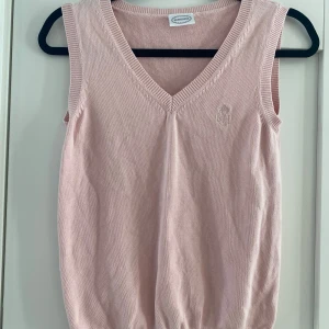 Rosa v-ringad stickad väst i strl M från Newhouse - Rosa v-ringad stickad väst i strl M från Newhouse.  Använd men i fint begagnat skick.  Mått Över bröstet: ca 42 cm Längd från axeln och ner: ca 55 cm  100% bomull   Kommer från ett djur och rökfritt hem.