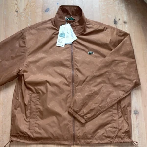 Lacoste Jacka - Säljer nu min helt nya Lacoste jacka! Endast testad. Köpte den i sommars i hopp om att ha den nu i höst men har tröttnat. Nypris: 2699kr, mitt pris: 1000kr, och det är inte satt i sten😉. Den är vattentät och har justerbar midja. Tags + kvitto finns! 