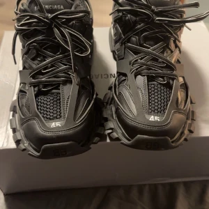 Balenciaga sneakers - Säljer ett par svarta Balenciaga sneakers med robust sula och snörning. Skorna har en modern design med Balenciaga-logga på sidan och undersidan. Perfekta för dig som vill ha en stilren och trendig look.