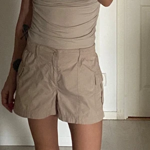 Beige shorts med fickor - Säljer ett par bekväma beige shorts från Gina Tricot. De har elastisk midja och praktiska fickor på sidorna. Perfekta för en avslappnad stil.