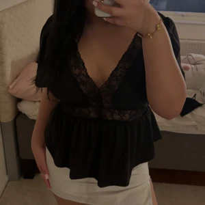 Svart blus med spetsdetaljer och svart korsett top - Snygg svart blus med djup v-ringning och spetsdetaljer. I sista bilden är en svart korsett topp. Första blusen kostar 50kr och den andra toppen kostar också 50kr. Båda är storlek M men den första blusen sitter väldigt lös så passar även L.