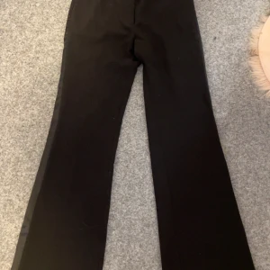 Svarta byxor från H&M - Snygga svarta byxor från H&M med en klassisk design. Byxorna har en rak passform och är perfekta för en stilren look. Tillverkade i ett bekvämt material som passar till många olika tillfällen.