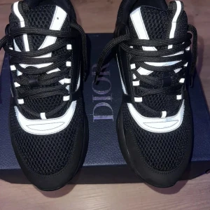 Svarta sneakers från Dior - Snygga svarta sneakers från Dior med vita detaljer och snörning. Skorna har en sportig design med mesh och syntetmaterial för en modern look. Perfekta för en stilren vardagsstil.