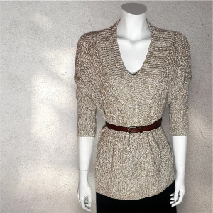 H&M beige stickad tröja med v-ringning - Säljer en mysig beige stickad tröja från H&M med v-ringning. Tröjan har trekvartsärmar och en ribbad kant vid ärmslut och nederkant. Perfekt för kyligare dagar. Färg: lite beige/ guld. Storlek: XS men passar också S 