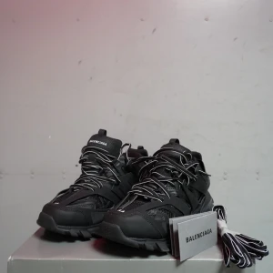 Svarta sneakers från Balenciaga - Snygga svarta sneakers från Balenciaga med robust design och tydlig logga på sulan. Skorna har snörning och en chunky sula som ger en modern look. Perfekta för dig som vill ha en stilren och trendig stil.