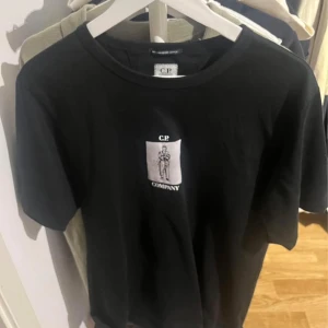 Svart t-shirt från C.P. Company - Snygg svart t-shirt från C.P. Company med tryck både fram och bak. Perfekt för en stilren look. Tillverkad i mjukt material för extra komfort.
