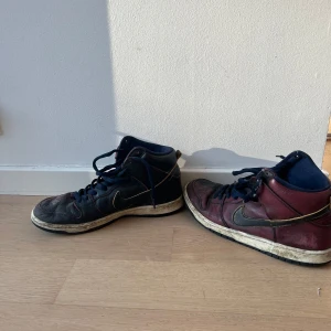 Nike sneakers i svart och vinrött - Säljer ett par Nike dunks i svart och vinrött med snörning. Skorna har en klassisk design med Nike-loggan på sidan och en bekväm sula. Perfekta för en avslappnad stil.