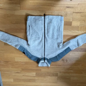 Grå fleecejacka från Woolrich - Säljer en mysig grå fleecejacka från Woolrich. Jackan har en dragkedja framtill och långa ärmar. Perfekt för kyligare dagar med sin mjuka och varma känsla.