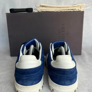 Valentino flycrews sneakers - Snygga blå sneakers från Valentino med vita detaljer och snörning. Skorna har en stilren design med en kontrasterande vit sula och är tillverkade i mocka. Perfekta för en trendig look, storlek 43 gott skick, hör av er vid intresse!!.