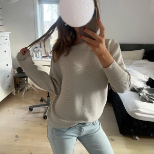 Grå-glittrig stickad tröja - Säljer en stilren grå glittrig tröja med långa ärmar. Perfekt för en avslappnad look. Tröjan har en mjuk och bekväm passform.