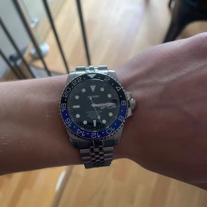 Seiko ”Batgirl” mod - Snygg Seiko-klocka med ett silverfärgat armband och en ceramic blå och svart bezel. Urtavlan är svart med datumvisning. Klockan är 40mm vilket passar väldigt många. Klockan är helt ny och köpt av klokkespesialisten.no, orderbekräftelse finns! Skriv privat för fler frågor!