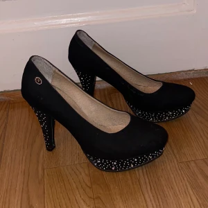 Svarta pumps  - Eleganta svarta pumps från Nysa med en glittrig klack och platåsula. Perfekta för att ge en touch av glamour till din outfit. Tyvärr är det några stenar som ramlat av men inget som märks jätte tydligt. 
