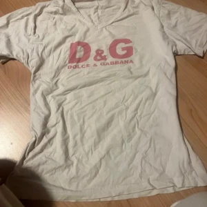 Vit t-shirt från Dolce & Gabbana - Säljer en vit t-shirt från Dolce & Gabbana med rosa D&G-logga på bröstet. Troligtvis fejk passar en s/ liten m