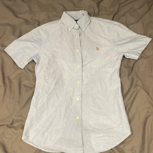 Kortärmad ljusblå Ralph Lauren skjorta - Snygg kortärmad skjorta helt perfekt för sommaren. Skicket är mycket bra o har inga tecken på användning. Nypris 1595kr. 