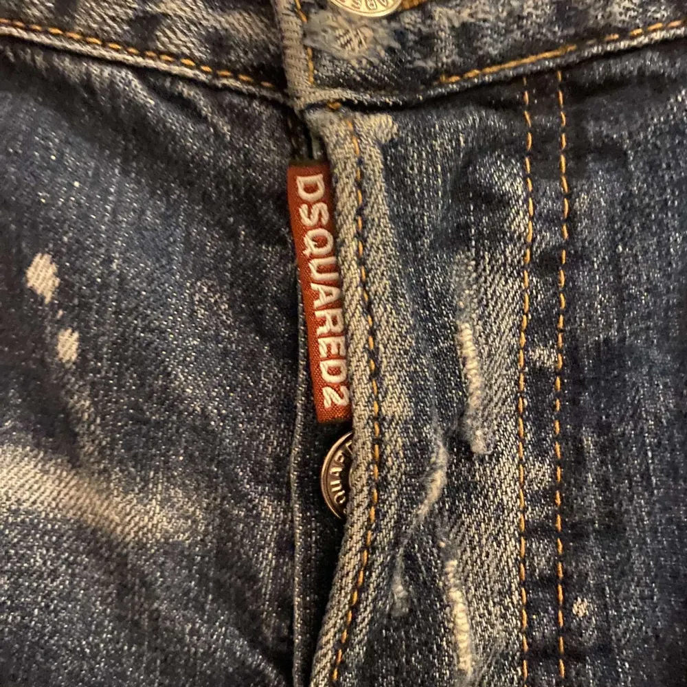 Snygga blå jeans från Dsquared2 med slitna detaljer och färgstänk. De har en klassisk femficksdesign och knappgylf. Perfekta för en trendig look. Storlek 48/S/M passar båda storlekar.. Farkut & Housut.