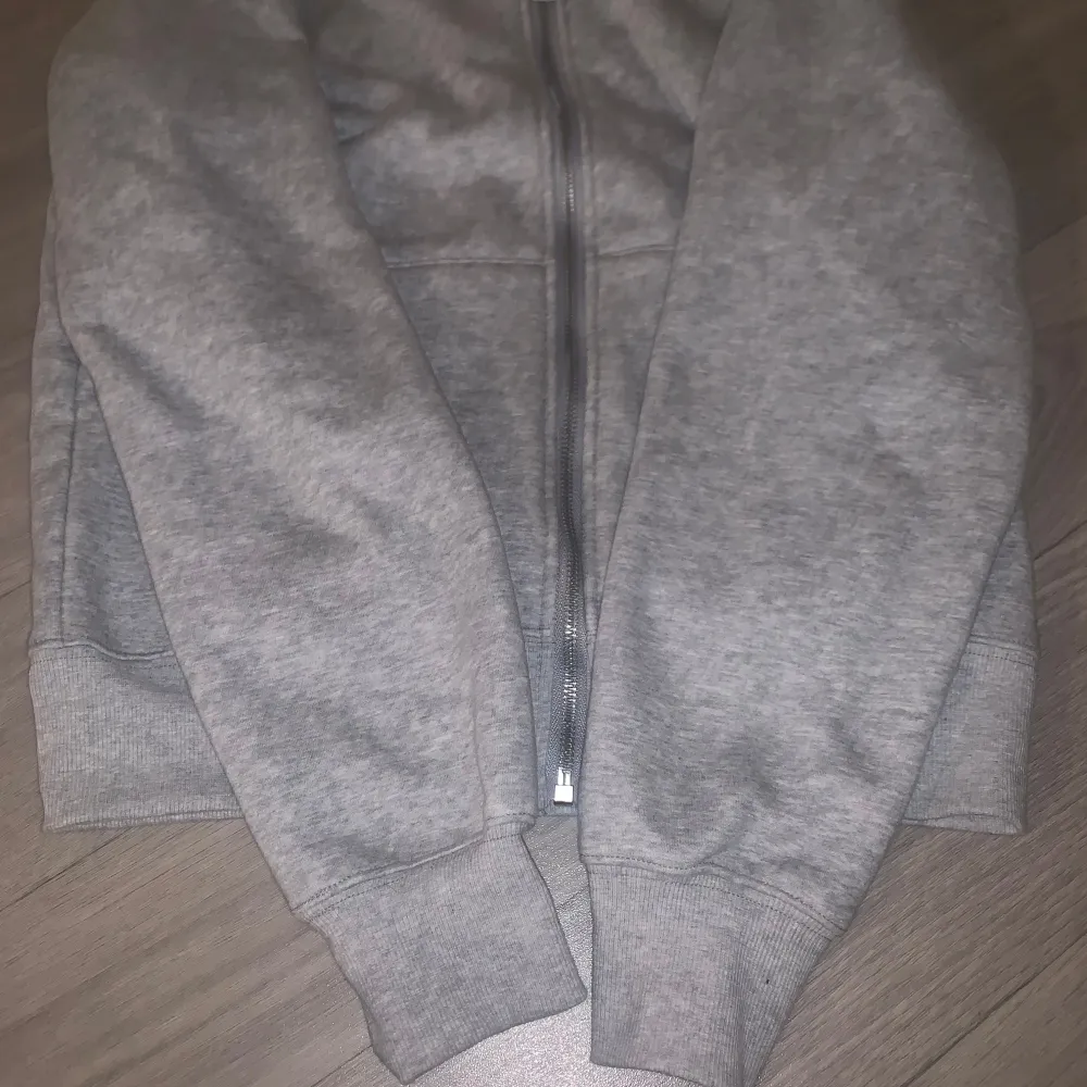 Mycket fin grå polo zip upp hoddie med mörkblå logo som är märklig och väldigt unik, materialet är jättte skönt och värdigt för det kalla vädret. Hoodies.