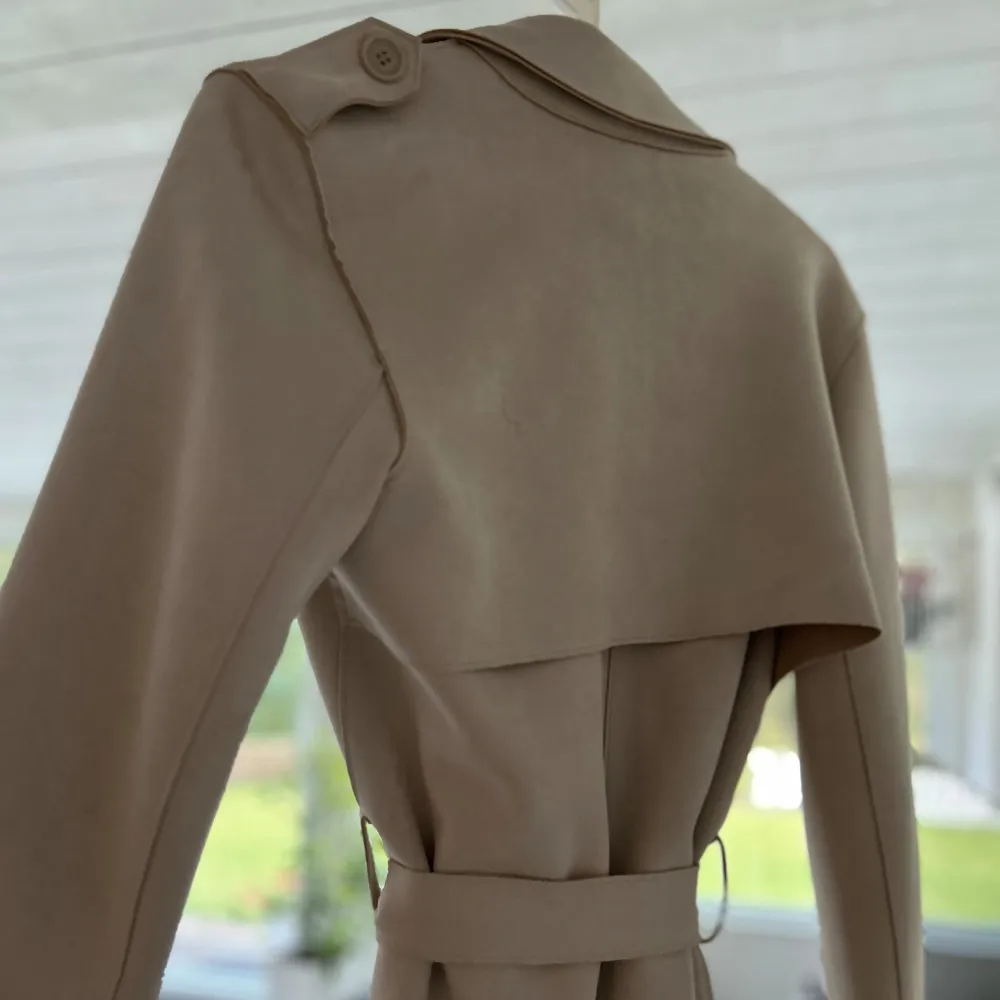 Säljer en superfin beige trenchcoat från Zara i storlek s/xs. Den har en klassisk design med knappar och ett bälte i midjan för en snygg passform. Perfekt för vår och höst! Ärmarna är långa och kappan har en stilren krage.🤎. Jackor.