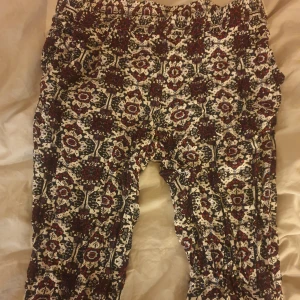 Mönstrade byxor i bomull - Säljer ett par supercoola mönstrade byxor i bomull. De har ett unikt blommigt mönster i svart, rött och vitt. Perfekta för en avslappnad stil eller en bohemisk look. Byxorna är bekväma och har en loose passform. Super sköna och tunnare i tyget.