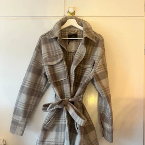 Kappa bikbok  - En snygg rutig jacka med en krage och en bälte. Den har två fickor på framsidan och knappar framtill. Den är i storlek S men den är stor i storlek  Kappan är lite lilla aktig