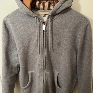 Burberry zip hoodie  - Säljer denna hoodie då den inte används. Inga skador på tröjan. Den är i ett väldigt fint skick. Tröjan är i storlek M och är mindre i storleken. Jag är 178 och den sitter perfekt på mig. Skriv för fler bilder.