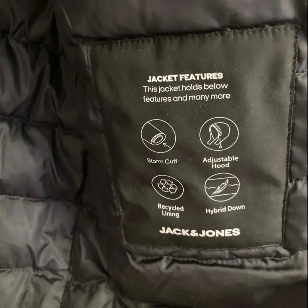 Säljer en svart jacka från Jack & Jones. Den har en justerbar huva och stormmuddar för extra skydd mot väder och vind. Insidan är fodrad med återvunnet material och jackan har hybrid dun för extra värme. Perfekt för kalla dagar!. Jackor.