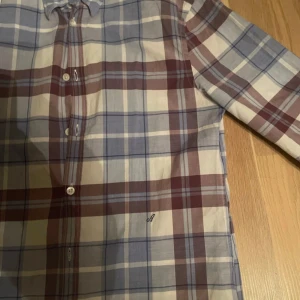 Rutig skjorta från Acne - Snygg rutig skjorta från Acne i blått, vitt och rött. Skjortan har långa ärmar och knappar framtill. Perfekt för en stilren look med en touch av färg. Passar bra till både jeans och chinos. Sitter som en S tveka inte att höra av er med frågor🙌