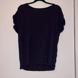 Mörklila topp från Aware - Säljer en stilren jättemjuk blå topp från Aware. Toppen har en rund halsringning och korta ärmar. Storlek S