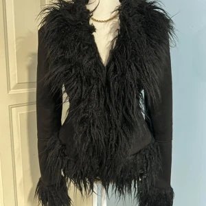 Svart jacka med fuskpälsdetaljer - Snygg svart fejk-mocka-jacka från boohoo med fluffiga fuskpälsdetaljer längs krage och ärmslut. Tyvärr han jag bara testa den en gång innan jag bytte stil igen… nyskick🖤🐾