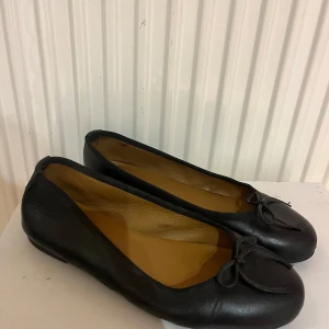 Svarta ballerinaskor  - Eleganta svarta ballerinaskor i skinn med en söt rosett. Perfekta för en stilren look och bekväma att bära hela dagen. Dom är i fint skick och inte mycket använda pga. fel storlek. Nypris ca 2000kr. Prisk kan diskuteras vid snabb affär💕