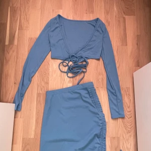 Blå kjol med snörning - Snygg blå kjol med snörning på sidan som ger en cool detalj. Kjolen har en normal passform och är perfekt för att skapa en stilren look. Matcha med en topp för en komplett outfit.