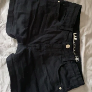 Låg midjade ! Svarta shorts från LAB Industries - Snygga svarta shorts från LAB Industries. Dom är andvända ett få tal någon ger men fins inga täcken på det dom är hela och har en till liten ficka under den stora på framsidan, shortsen sitter tajt och är  PERFECKTA men jag har växt ur dom nu så jag måste tyvärr sälja dom, shortsen ör i storlek 152 men jag med storlek 36 får fortfarande på mig dom över rumpan men kan inte knäppa, har du st 32 får du nog på dig dom bra, kontakta för mer information elle mer detaljerade bilder 💞