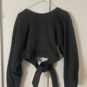 Svart croppad tröja med öppen rygg och knyt - Säljer denna fina svart croppade tröja med långa ärmar med öppen rygg och knytning i ryggen. Använd ett fåtal gånger och finns inte på NA-KD längre🖤🖤🖤
