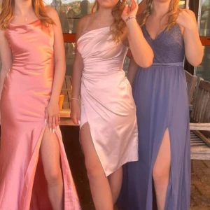 Ljusrosa Balklänning - Hej! Säljer nu min superfina balklänning. Den ljusrosa i mitten på bilden!! Den är i ljusrosa satin och med en slits. Passar perfekt nu till baler eller bara som en finare klänning. Den är i storlek 38. Köpte den från SEfashion 2023 och har endast använt den på min bal. Nypris: 2000kr Mitt pris: 1000kr + ev frakt