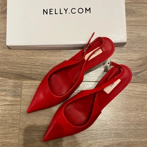 Pointy Low Slingback, röda klackar från Nelly  - Spetsiga klackskor från Nelly i en så snygg röd färg, tyvärr fel storlek för mig och tiden att skicka tillbaka har gått ut. Helt nya med original förpackning. Modellen heter ”Pointy Low Slingback”. Stl 37, men skulle säga att de är ganska stora i storlek. Passar 38
