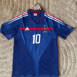 France 2004-06 Home Shirt (S) (klassisk) - Frankrikes hemmatröja 2004-06, buren av spelare som Henry, Zidane, Desailly och Thuram när laget nådde kvartsfinal i EM 2004. Tillverkad av Adidas.