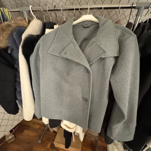 Grå kappa med knappar - Snygg grå kappa med stora knappar och bred krage. Perfekt för kyligare dagar och ger en stilren look. Passar bra till både jeans och klänning.