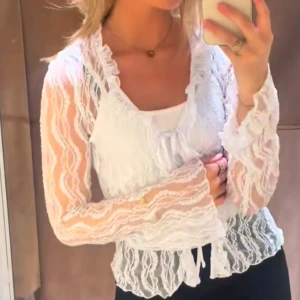 Vit spetsblus från Pieces - Säljer en elegant vit spetsblus från Pieces. Blusen har långa ärmar och en v-ringad design med knytning framtill. Perfekt för att ge en romantisk touch till din outfit. 💫