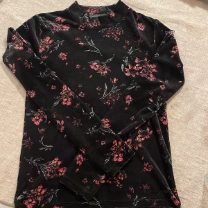 Svart sammetströja - Säljer en svart långärmad tröja med vackert blommönster i rött och rosa. Tröjan har en mjuk och bekväm känsla, perfekt för både vardag och speciella tillfällen. Passar utmärkt till höst- och vårgarderoben. Pris kan diskuteras.