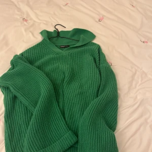 Grön stickad tröja från Shein - Säljer en snygg grön stickad tröja från Shein. Tröjan har en v-ringad hals och långa ärmar med ribbade muddar. Perfekt för kyligare dagar och ger en skön och avslappnad stil. Passar bra till jeans eller kjol för en trendig look.