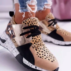 Leopardmönstrade sneakers med gulddetaljer - Snygga sneakers med leopardmönster och gulddetaljer. Skorna har en chunky sula med svart och vit stänkmönster. De är dekorerade med svarta snören och har en unik design som sticker ut.