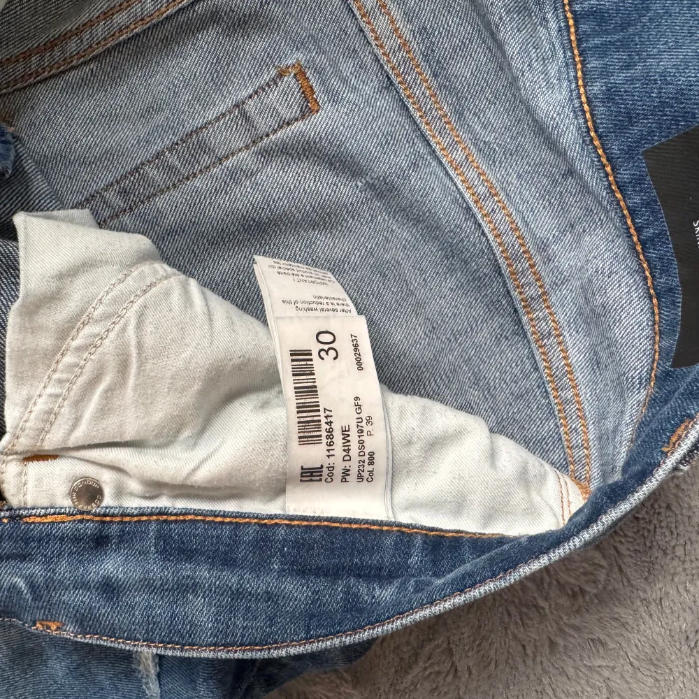 Säljer ett par snygga blå jeans från Dondup med slitna detaljer och en klassisk femficksdesign. Jeansen har en knappgylf och är tillverkade i ett bekvämt denimtyg. Perfekta för en avslappnad stil. Nästan helt nya!! Bara att höra av sig till oss vid frågor eller funderingar.. Jeans & Byxor.